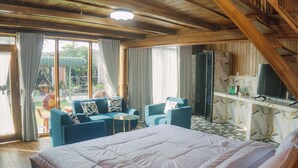 A bedroom with a large bed, two blue armchairs, a small table, and a kitchen area with a marble countertop.