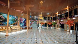 A spacious lobby with a marble floor, large paintings, and a chandelier.
