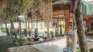 An indoor garden with a fountain, wooden flooring, and hanging plants.