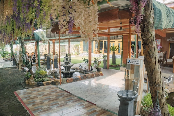 Un jardin intérieur agrémenté d’une fontaine, d’un plancher en bois et de plantes suspendues.