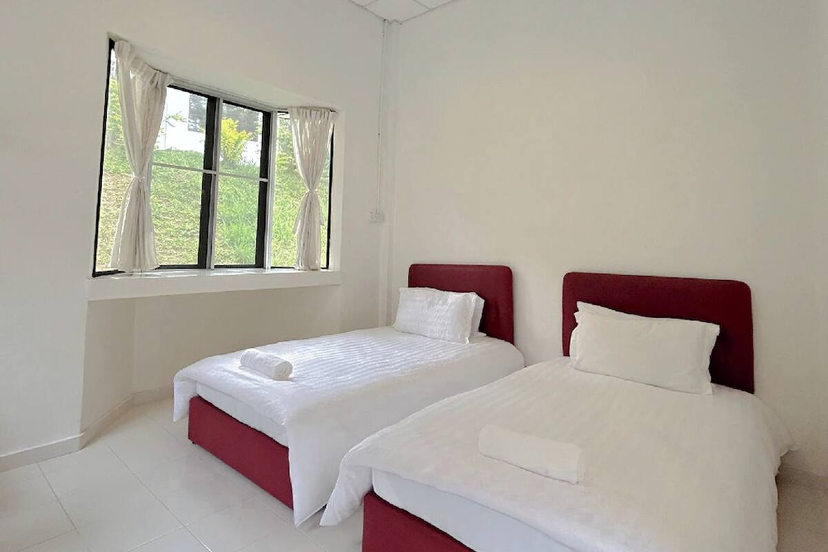 A room with two beds, a window with curtains, and a tiled floor.
