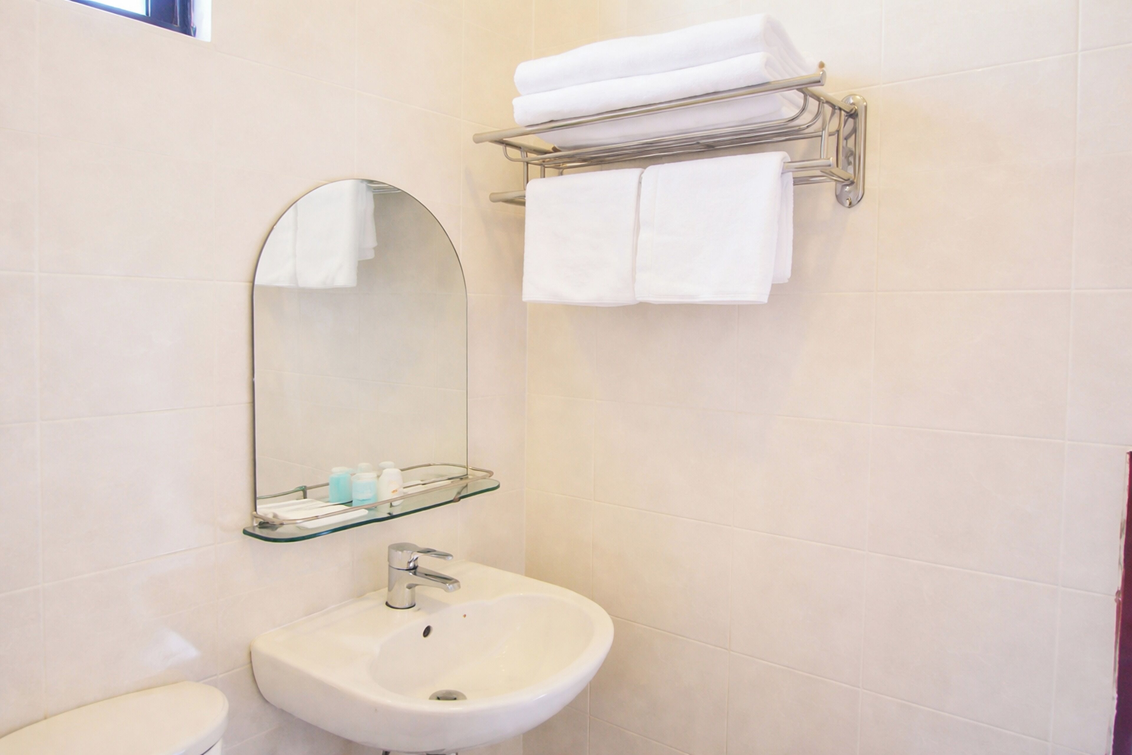 Un baño con lavamanos, espejo y toallero.