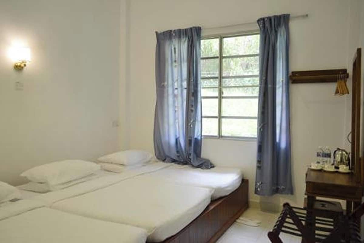 A simple room with a bed, a desk, and a window with curtains.