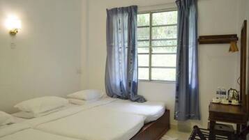 A simple room with a bed, a desk, and a window with curtains.