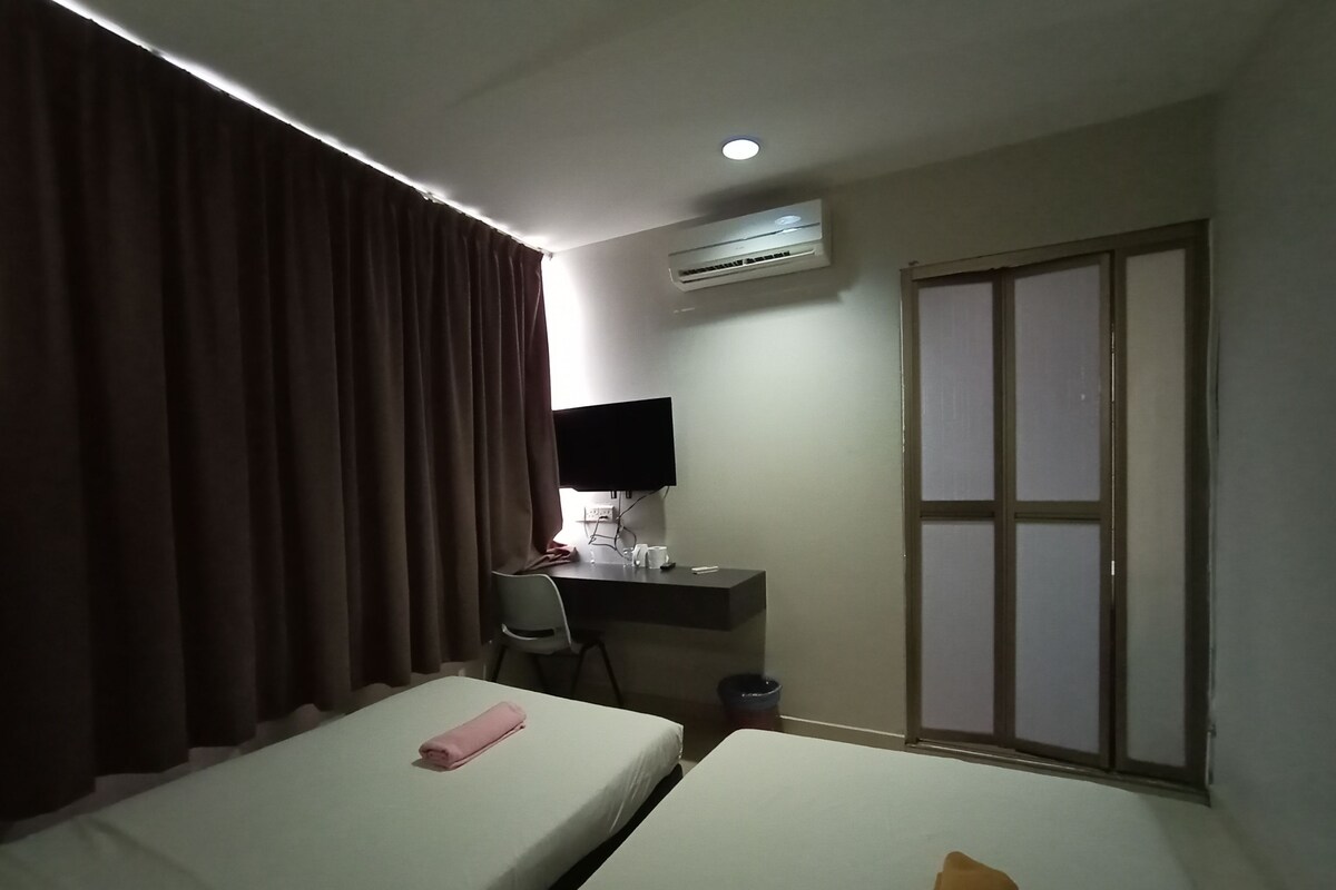 A hotel room with two beds, a desk with a chair, an air conditioner, and a sliding door.