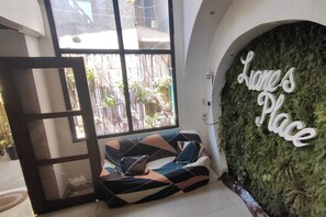 Um quarto com um sofá, uma janela e uma parede com uma placa que diz 'Liane's Place'.