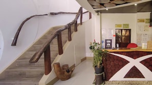 A staircase with wooden railings, a reception desk, and a plant.
