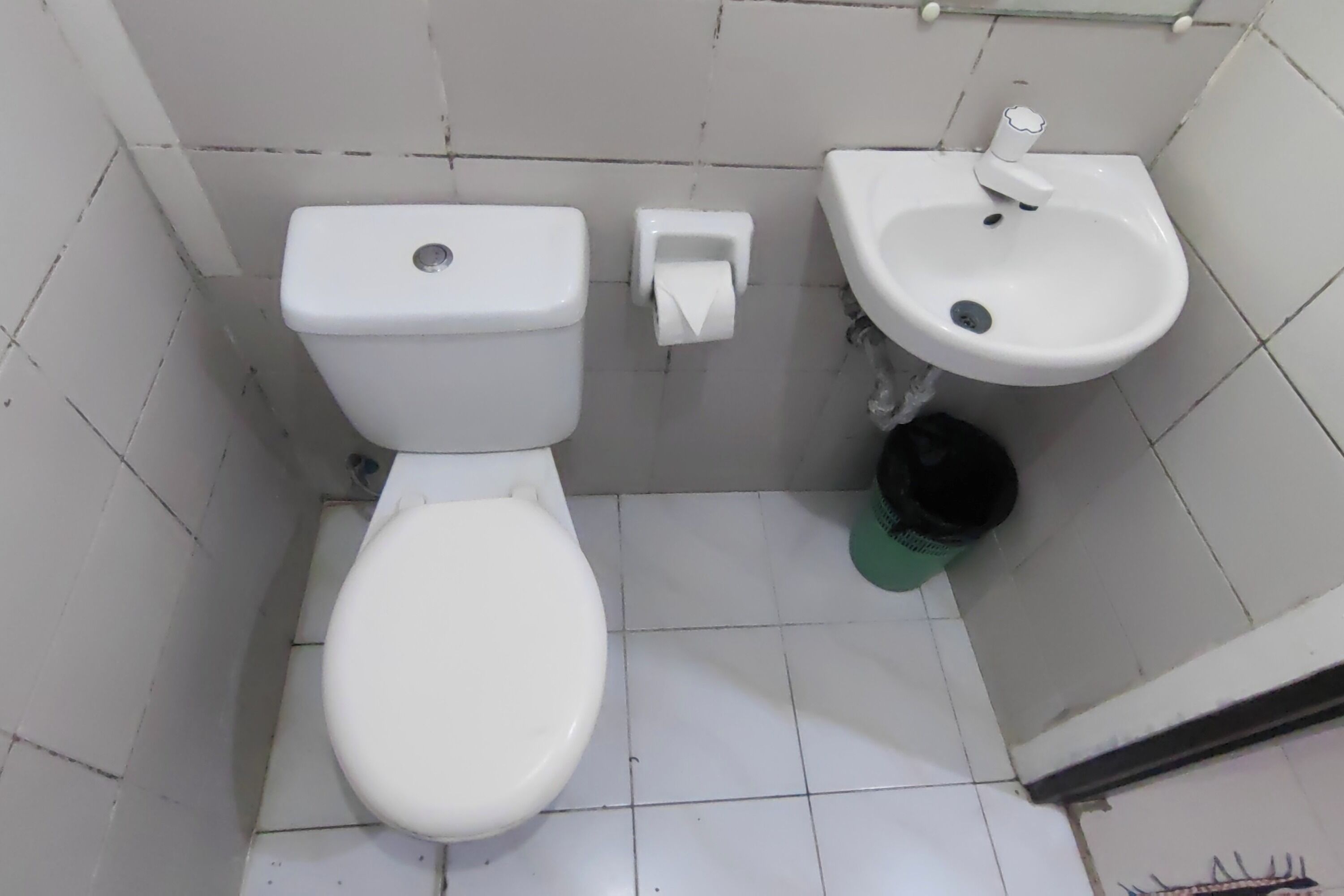 Une petite salle de bain simple, équipée d’un WC, d’un lavabo et d’une poubelle.