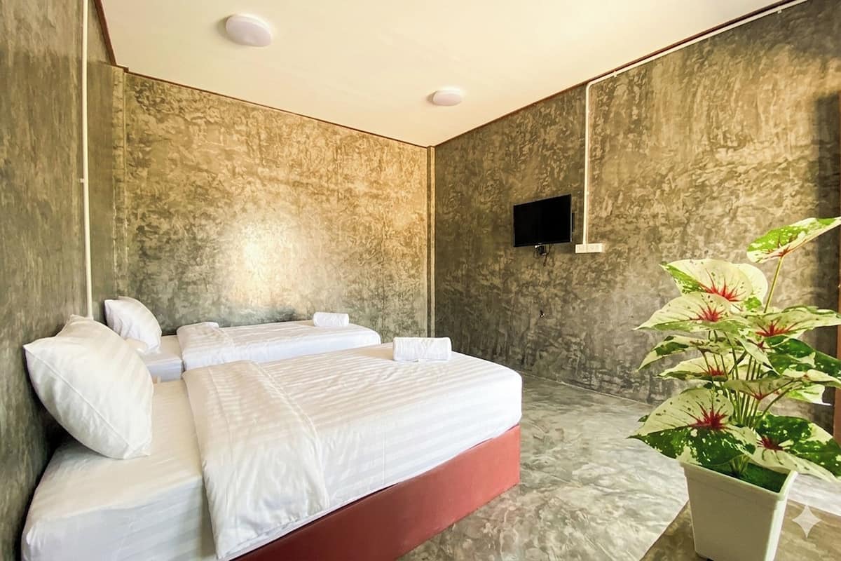 A hotel room with a large bed, a flat-screen TV mounted on the wall, and a potted plant.