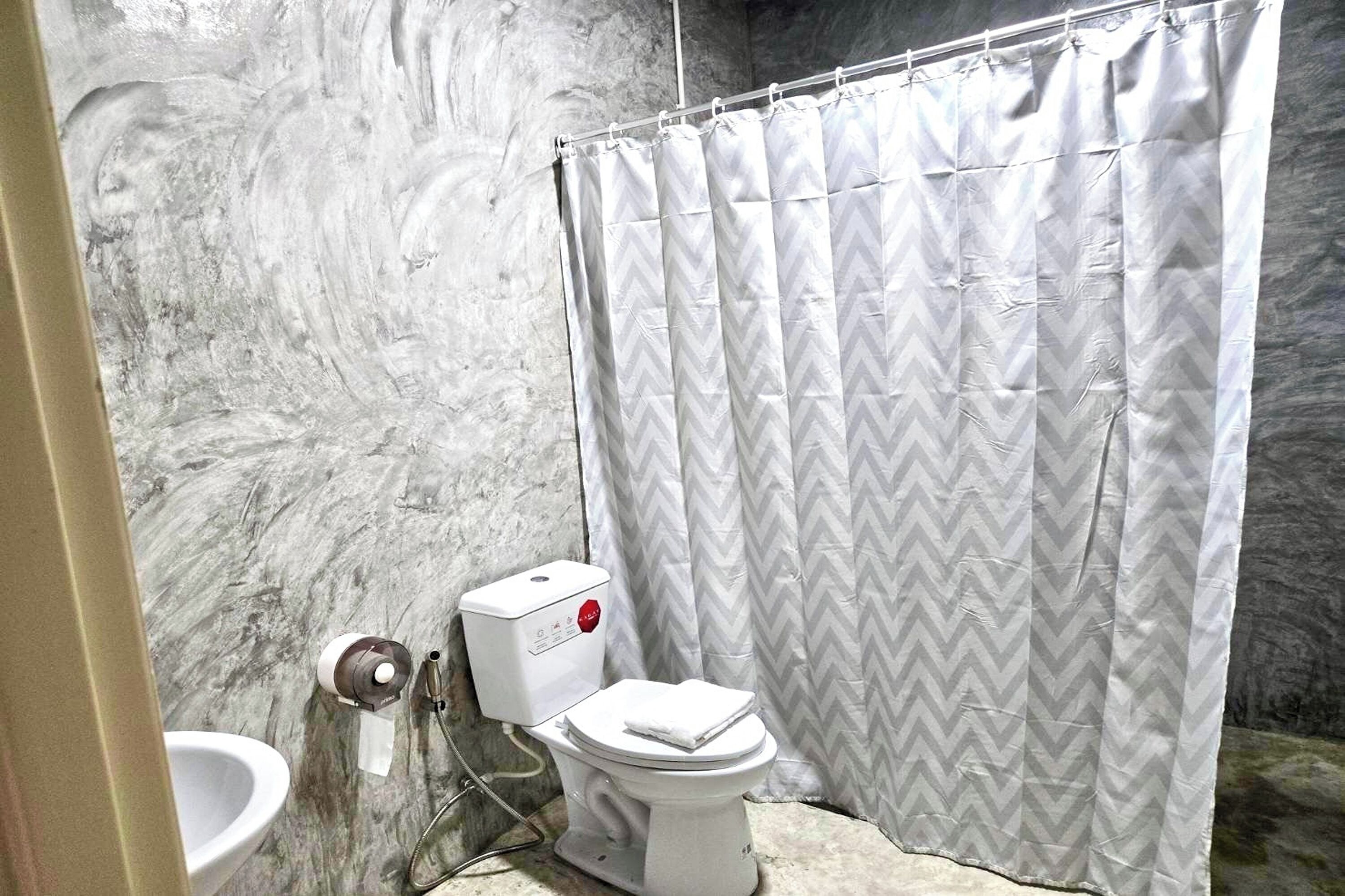 A bathroom with a toilet, bidet, and a shower curtain.