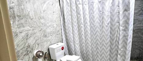 A bathroom with a toilet, bidet, and a shower curtain.
