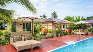 Un espace aménagé au bord de la piscine, avec des chaises longues, des parasols et une piscine.