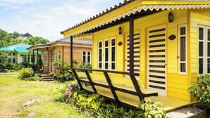 Un bâtiment jaune doté d’un porche, d’un escalier et d’un petit jardin.