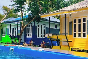A row of colorful beach houses with a swimming pool in the foreground. - Phetmanee Resort (Ko Yao)
