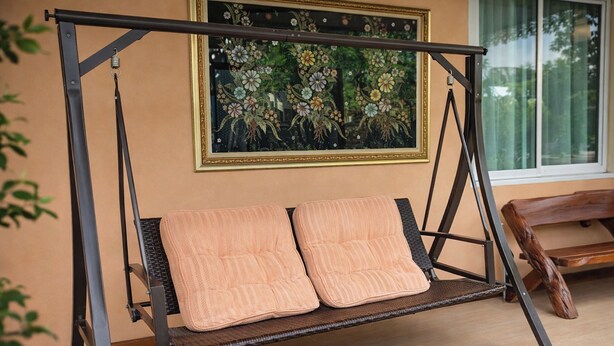 Una poltrona a dondolo con cuscini, un quadro appeso al muro e una finestra con vista.