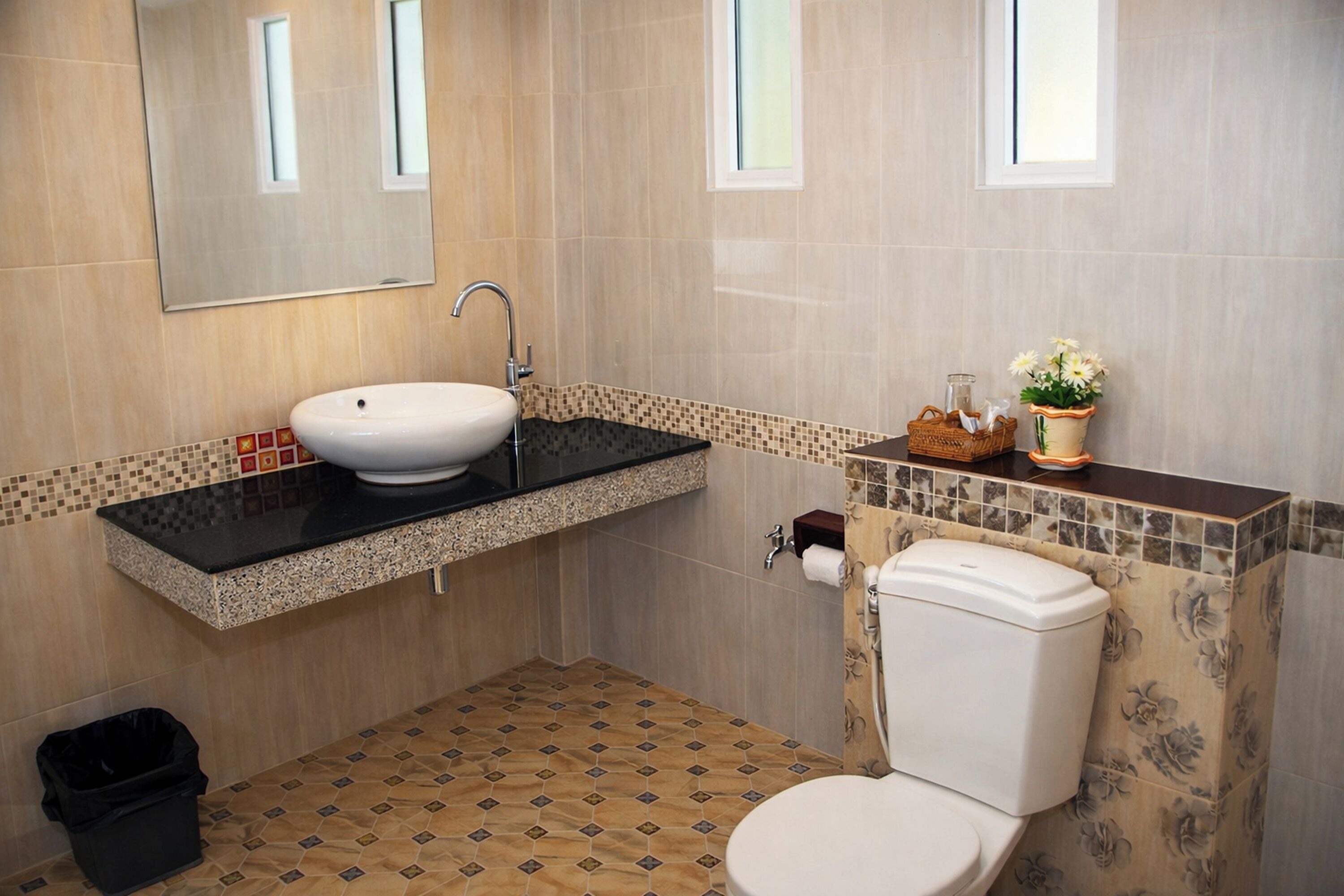 A bathroom with a sink, toilet, and trash bin.
