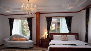 Ein Schlafzimmer mit Bett, Sofa, einer Chandelierleuchtre und einem Nachttisch.