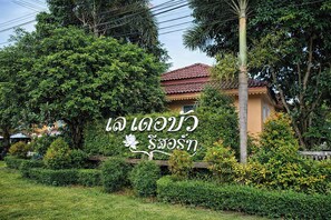 Un edificio con un letrero en idioma extranjero, rodeado de exuberante vegetación y una palmera.
