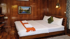 Una stanza con rivestimento in legno, un letto, un quadro appeso al muro e un lampadario.