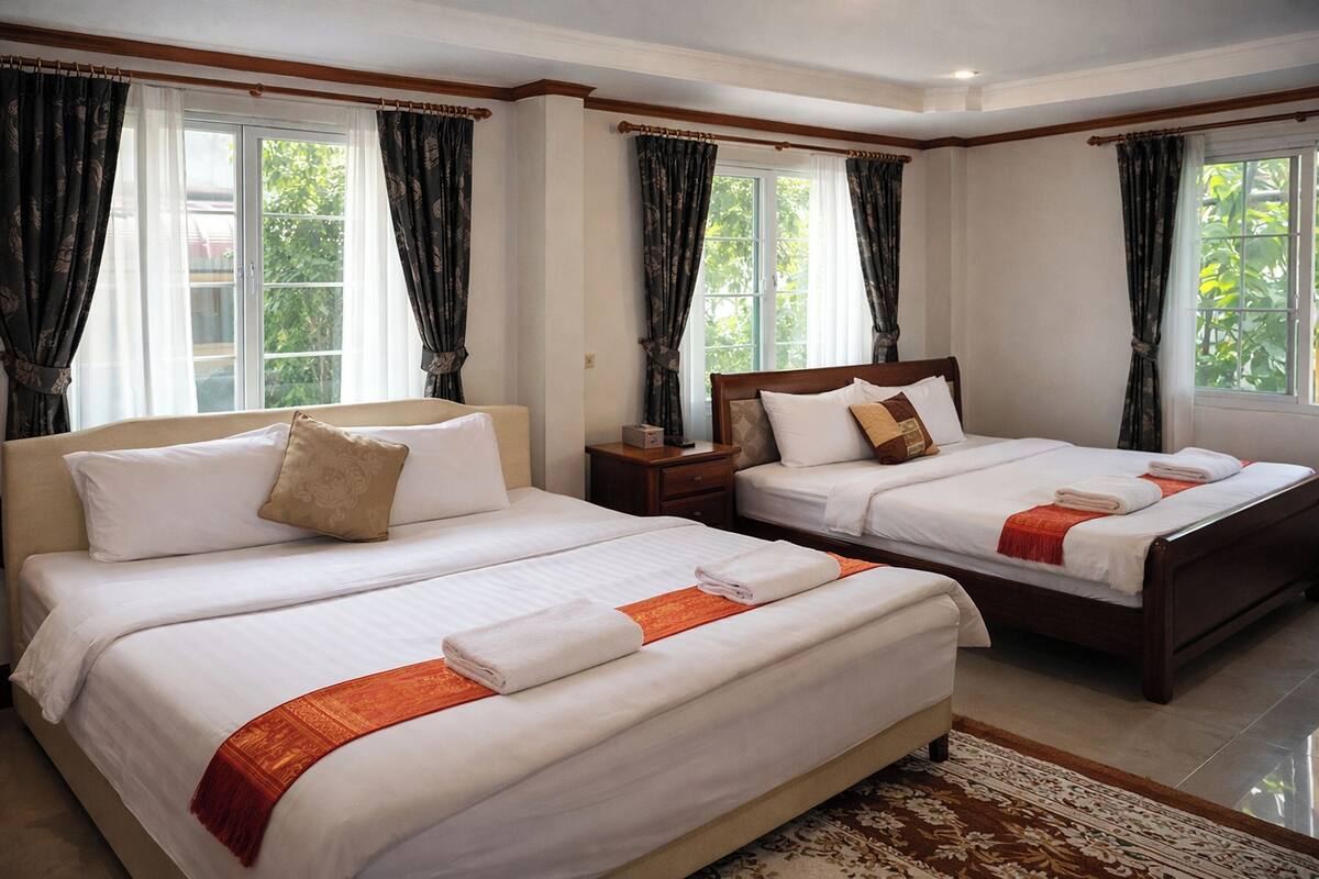 Een hotelkamer met twee bedden, een nachtkastje en een raam met gordijnen.