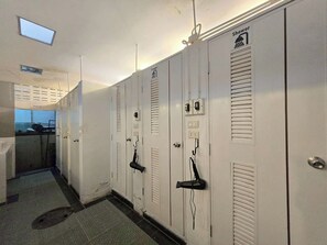 A row of white lockers with shower symbols, a small window, and a door with a handle. - Nearthepark Backpack Hostel Night Bazaar (Chiang Mai)