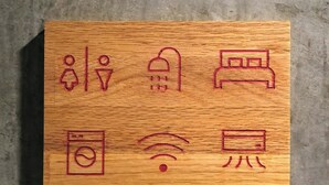 Bloco de madeira com ícones representando um banheiro, uma cama, máquina de lavar, símbolo de Wi-Fi e uma televisão.