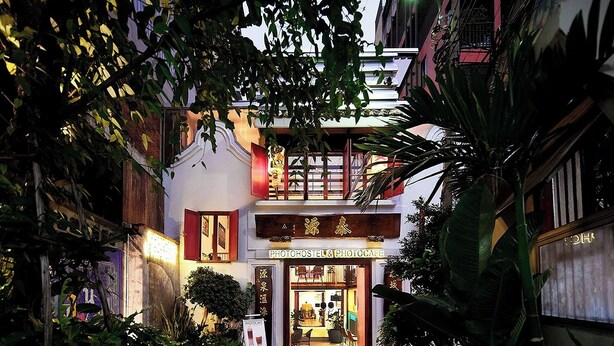 Entrada de hotel com uma placa mostrando 'PHOTOCAFE' e 'HOTEL & PHOTOCAFE'.