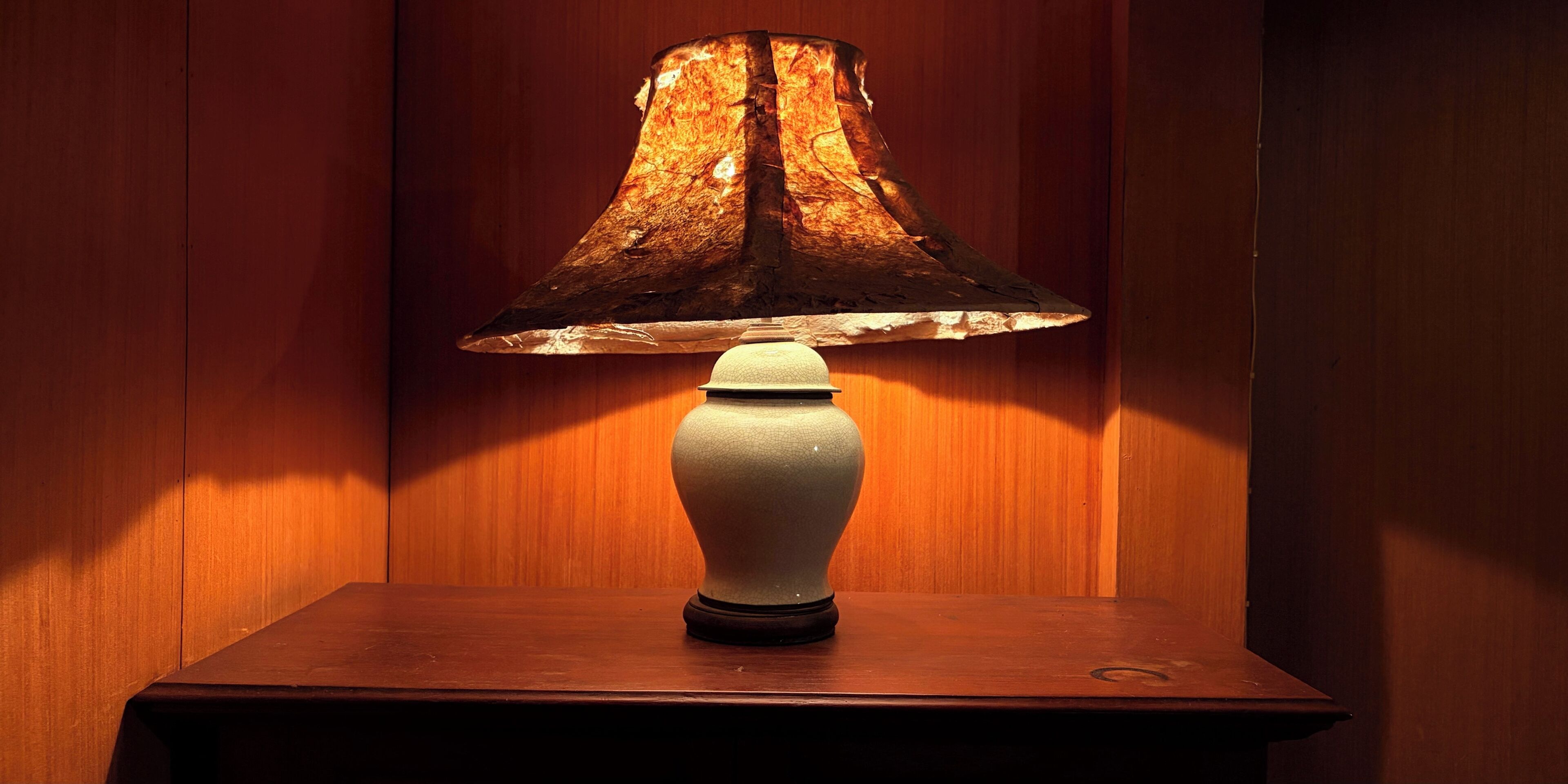 Une table sur laquelle se trouve une lampe, placée devant un mur lambrissé.