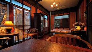 Une pièce chaleureuse avec une table en bois, une chaise, une lampe, un lit et une fenêtre avec des rideaux.
