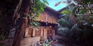 Un edificio de madera con balcón, rodeado de exuberante follaje tropical.