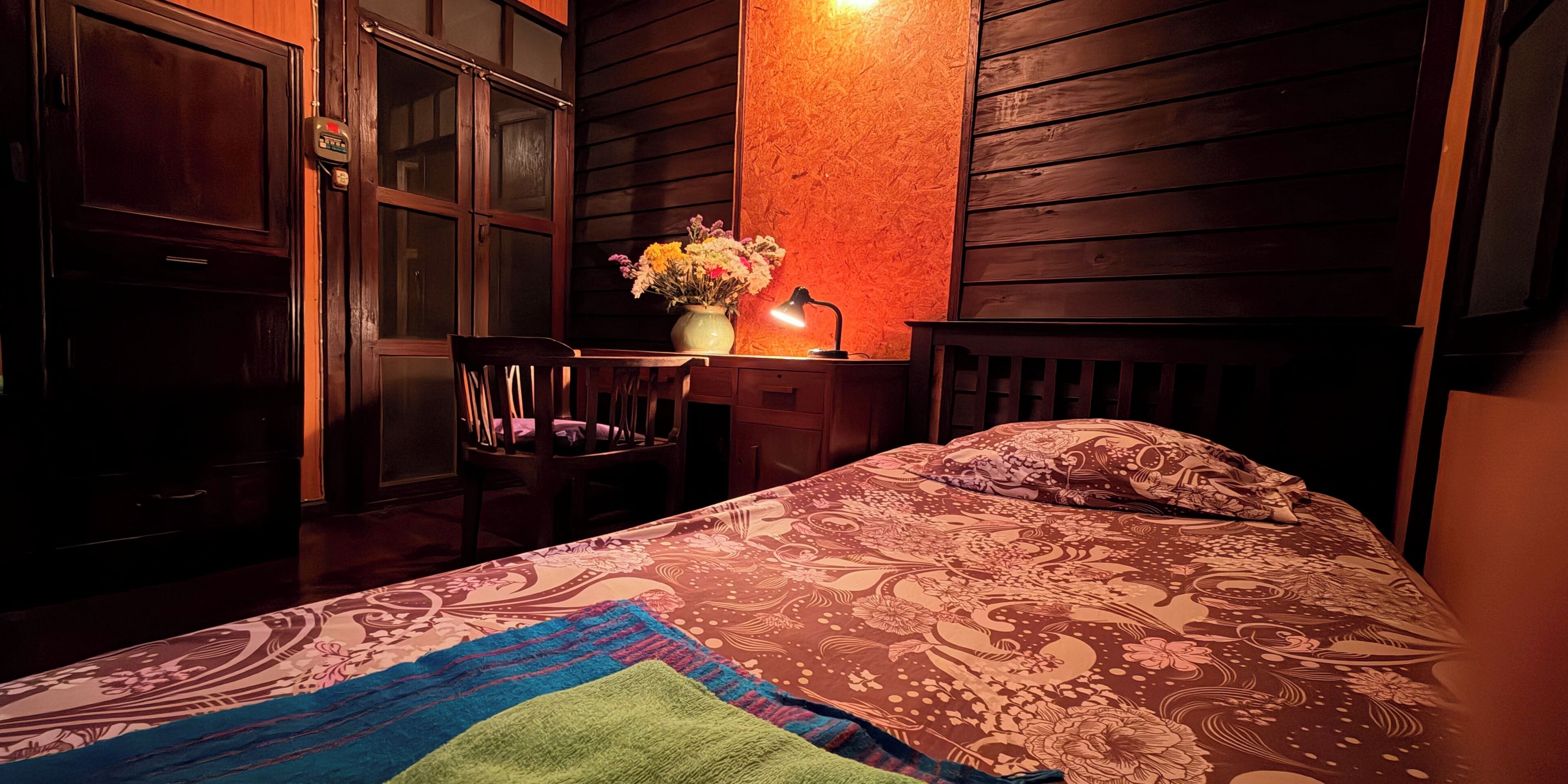 Une chambre à coucher avec un lit, une chaise, un bureau et une table de chevet.