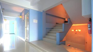 A modern interior with a staircase, a door with a sign, and a hallway. - Chill Guest (Bangkok)