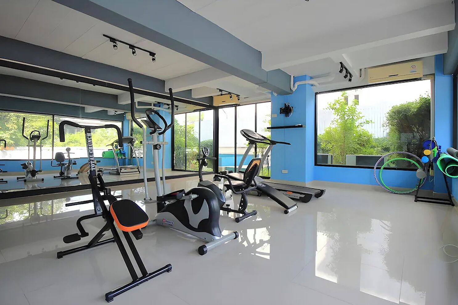 Une salle de sport moderne, dotée d’équipements d’exercice, de grandes fenêtres et d’un sol propre et brillant.