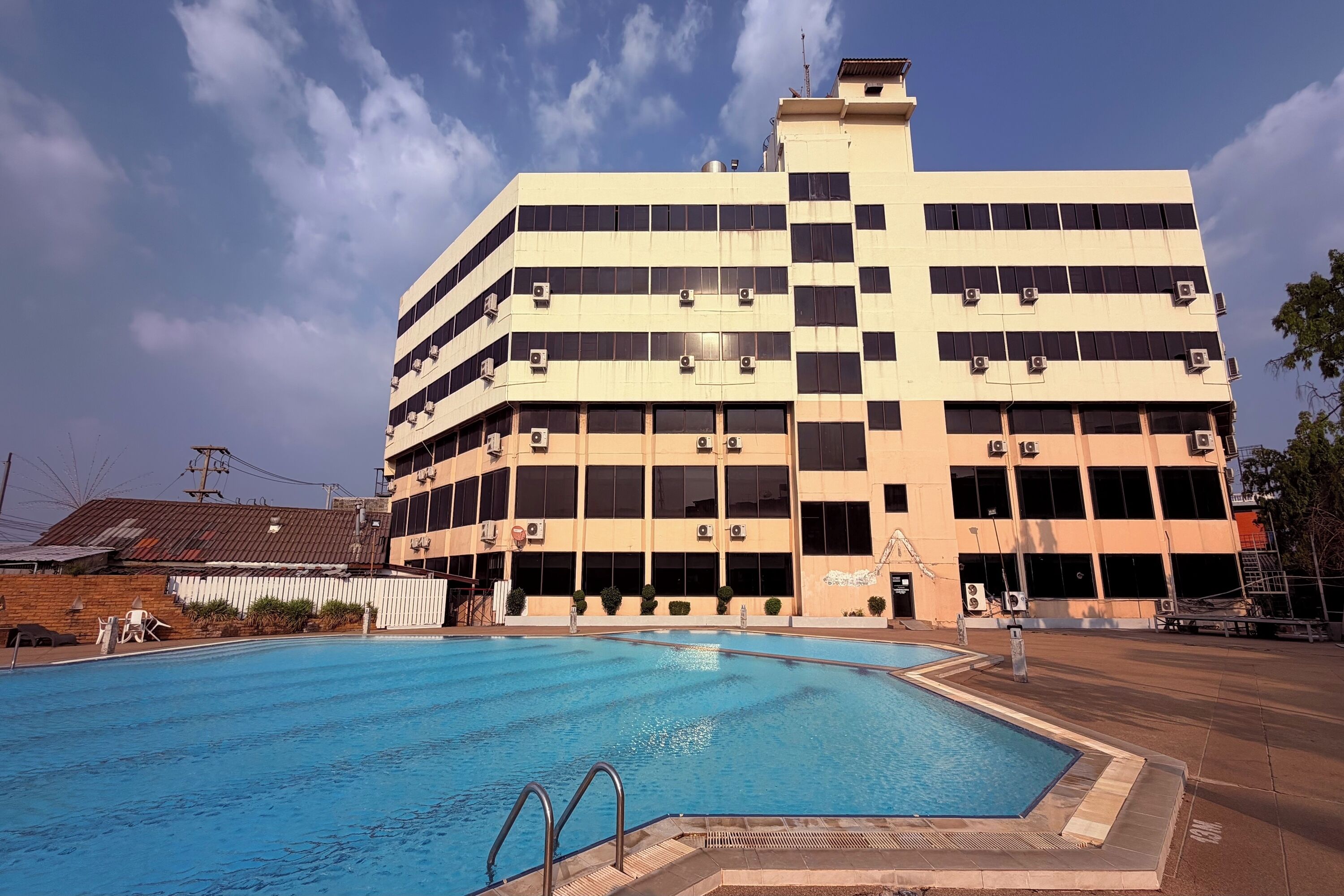 A multi-story building with a swimming pool in front.