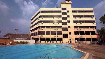 A multi-story building with a swimming pool in front.