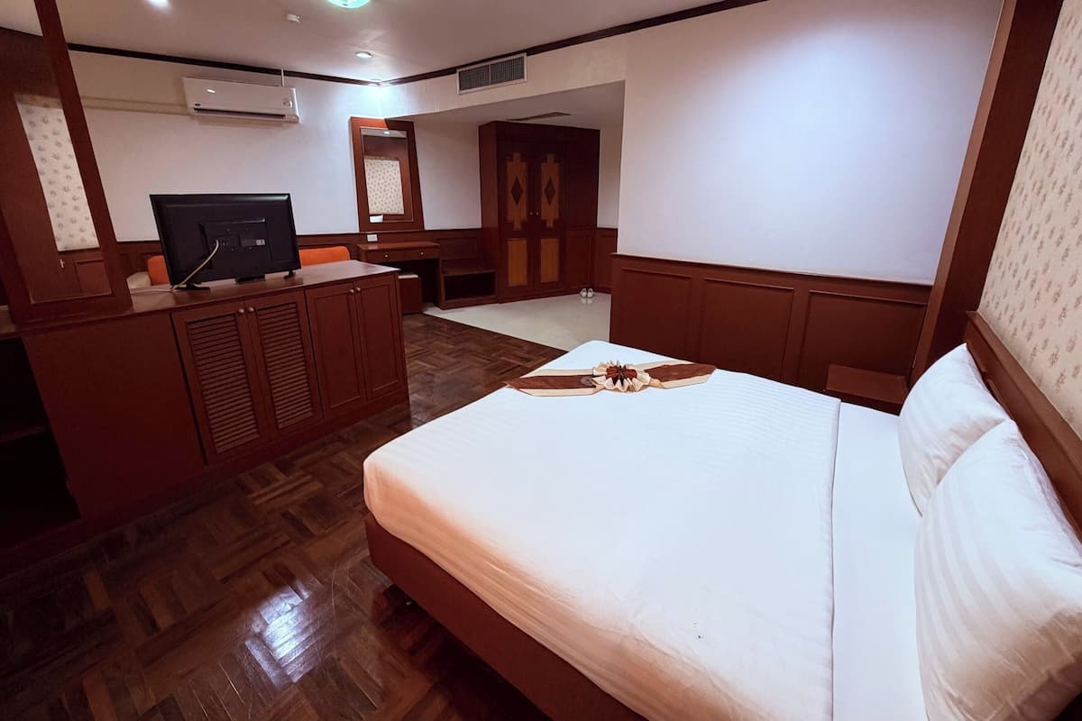 Une chambre d’hôtel équipée d’un lit, d’un bureau, d’une télévision et d’une armoire.