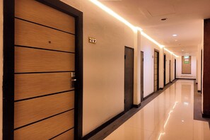 Pasillo de hotel con puertas de madera, un letrero con número y un suelo limpio y brillante.