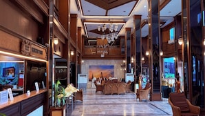 A lobby with a reception desk, seating area, and a large mural. - G2 Ayutthaya (Uthai)