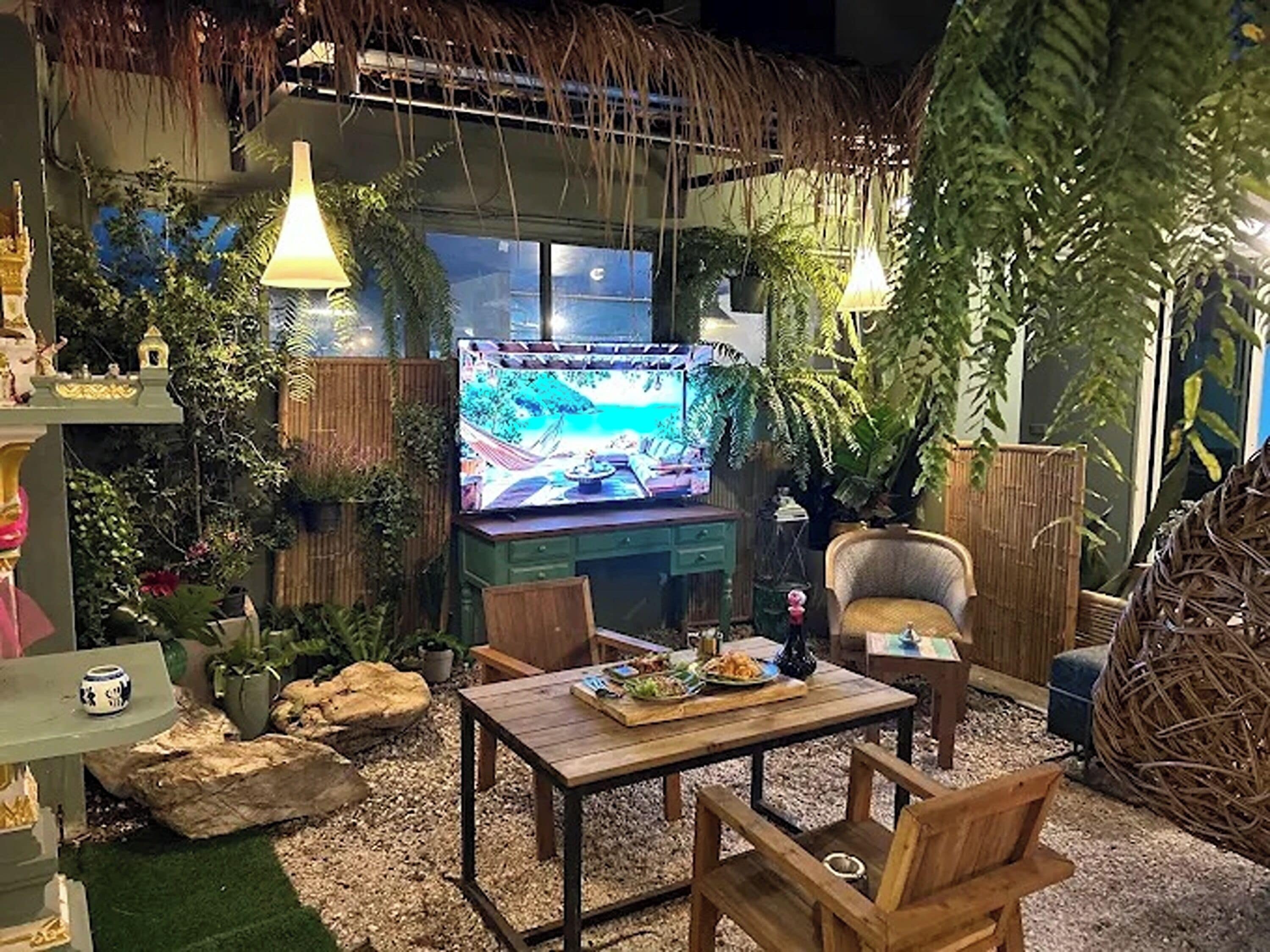 A cozy indoor setting with a television, wooden furniture, and lush greenery.