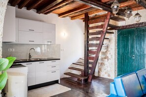 A kitchen with white cabinets, a black countertop, and a wooden staircase. - Art House Seaview & Jacuzzi Spartylas Sleeps 4 (corfu)