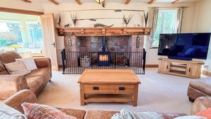 A cozy living room with a fireplace, a television, and comfortable seating. - Little Balloch Angus Glens (Kirriemuir)