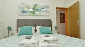 Un letto rifatto con cura, con una coperta a motivi geometrici, due cuscini e un asciugamano piegato.