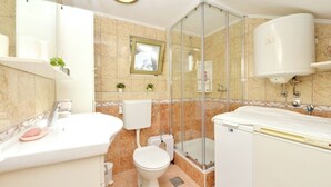 Un bagno moderno con box doccia in vetro, lavandino bianco e water.