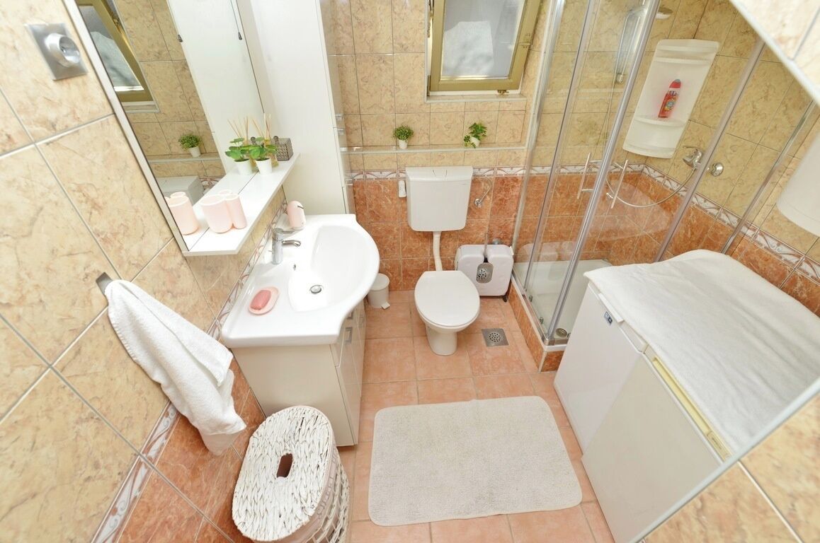 A compact bathroom with a sink, toilet, and shower.