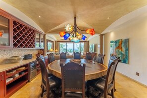 A dining area with a round table, chairs, a chandelier, and a view to the outside. - Ocean Blue Beachfront Condo in Puerto Aventuras (Puerto Aventuras)
