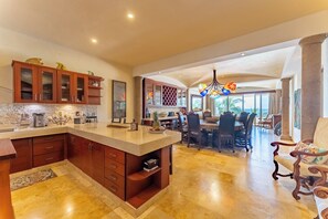 Una cocina amplia con una isla grande, armarios de madera y un comedor con vistas.