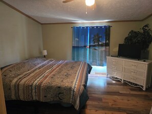 A bedroom with a bed, a dresser, a ceiling fan, and a view of a beach through a curtain. - Northern Nature Nest
3/Bed 2/Bath Pet Friendly, Trail Access-Luther, MI (Luther)