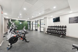 A gym with exercise equipment, a wall-mounted TV, and a rack of dumbbells. - Lux Mins to Mayo Clinic , Old Town & HonorHealth (Scottsdale)