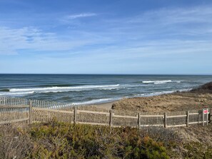 Ein Strand mit einer Holzbrüstung, Wellen und einem klaren Himmel.