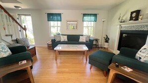 A living room with a sofa set, a coffee table, a fireplace, and a staircase. - 3BR Coastal Retreat ON Cape Cod Rail Trail near Nauset Light & Coast Guard Beach (Eastham)